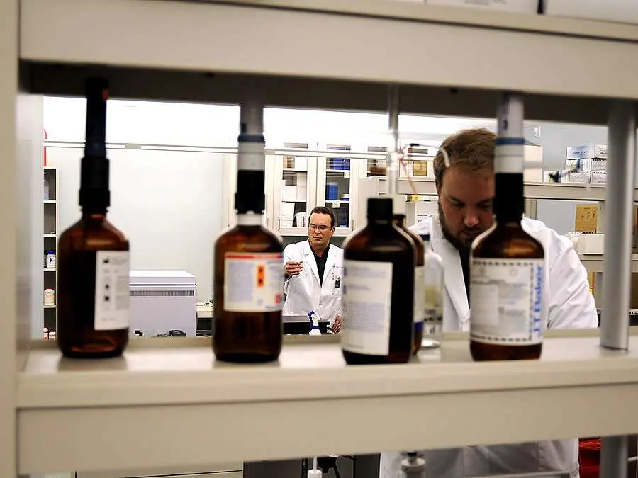 Panoramica di laboratorio di tossicologia con operatori al lavoro e flaconi di reattvi